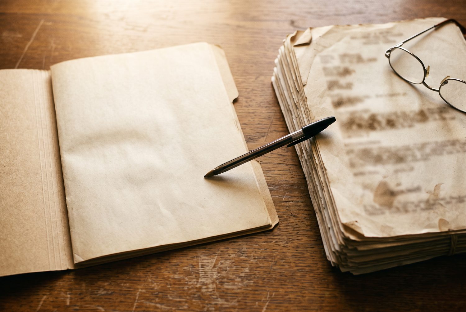 A medical file and a stack of military service records side by side with a pen laid across the gap between them